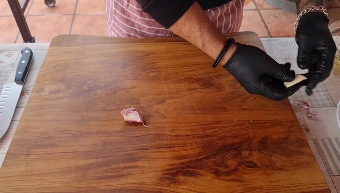 Mientras tanto, preparar los pimientos de piquillo: Calentar aceite en una sartén y añadir láminas de ajo.