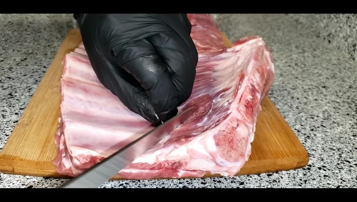 Quitar la membrana de la parte posterior del costillar con ayuda de un cuchillo y una servilleta si es necesario. (Opcional: Retirar exceso de grasa).