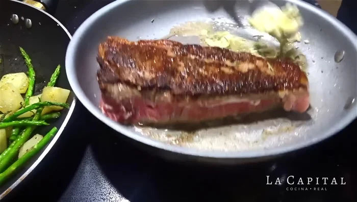 Baña el bife con la mezcla de mantequilla, ajo y romero para que absorba los sabores. Continúa la cocción los 4 minutos restantes.