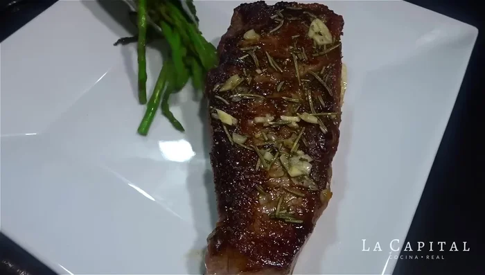Sirve el bife de New York con las papas y los espárragos.