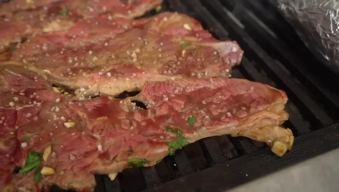 Asar la carne: Colocar la carne en la parrilla, sazonar con sal por ambos lados. Una vez que sueltan sus jugos, voltear. (262.84, 264.8)