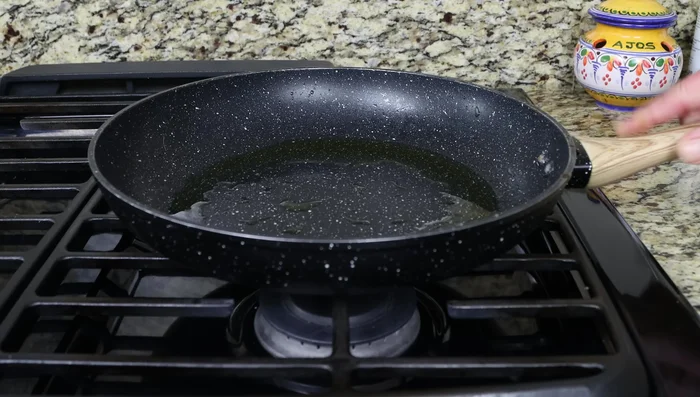 Calentar la sartén a fuego medio-bajo con 30 ml de aceite de oliva. Agregar la mezcla de patata y huevo, extendiéndola en una capa plana.