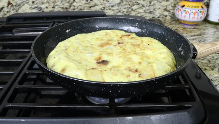 Retirar del fuego y deslizar la tortilla sobre una tabla de cortar.