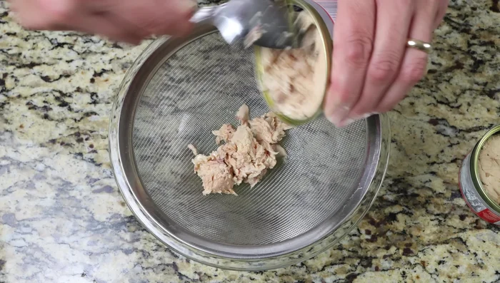 Escurrir dos latas de salmón y desmenuzarlo suavemente. Transferirlo a un tazón grande.