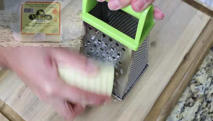 Ralla 240g (2 tazas) de queso y agrégalo a la masa. Mezcla hasta que todo esté bien integrado. Ajusta la consistencia de la masa añadiendo más líquido o harina si es necesario.
