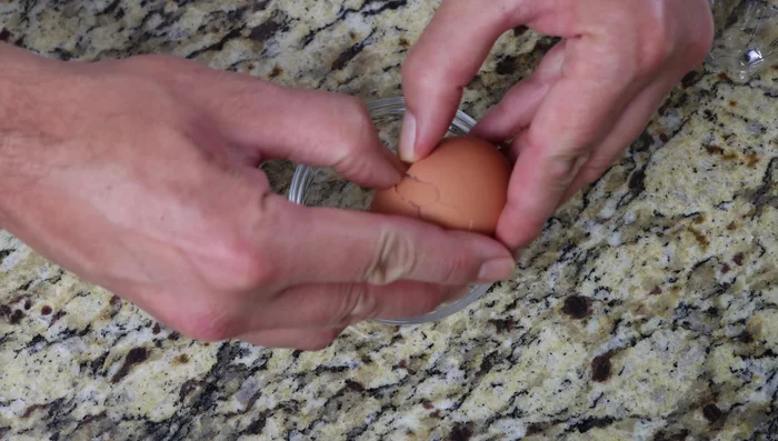 Romper los huevos en tazones individuales para evitar cascaras y añadirlos a la sartén, creando pequeños bolsillos (235.36).