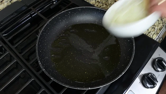 Agregar la cebolla y el ajo a la sartén caliente y mezclar para cubrirlos con el aceite (80).