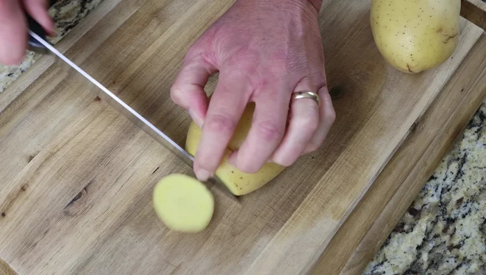 Cortar dos papas medianas en rodajas de 1 cm de grosor. (75.439)