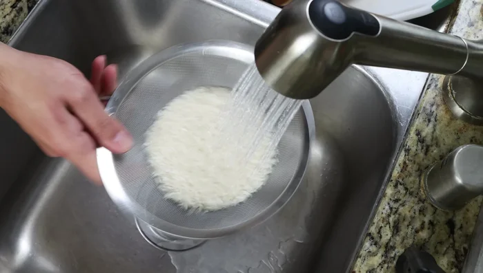 Enjuagar el arroz durante 1 minuto hasta que el agua salga clara.