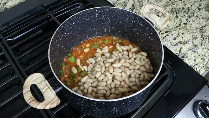 Agregar las judías enjuagadas, el caldo vegetal, las hebras de azafrán y la hoja de laurel a la sartén. Llevar a ebullición.