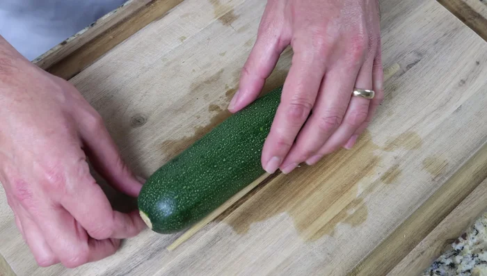 Colocar los calabacines sobre palillos chinos y cortarlos en rodajas de 1 cm de grosor, sin cortar completamente.