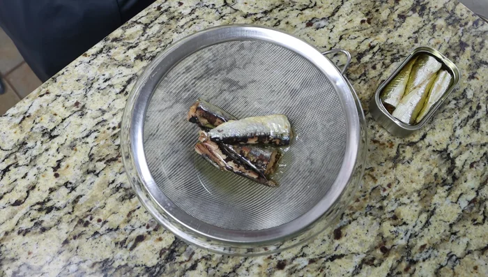 Escurrir suavemente las sardinas enlatadas en un colador fino con un cuenco debajo. Reservar el aceite.