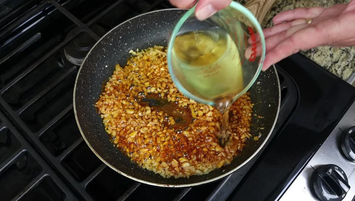Agregar el vino blanco seco (o caldo) y cocinar a fuego lento durante 2-3 minutos.