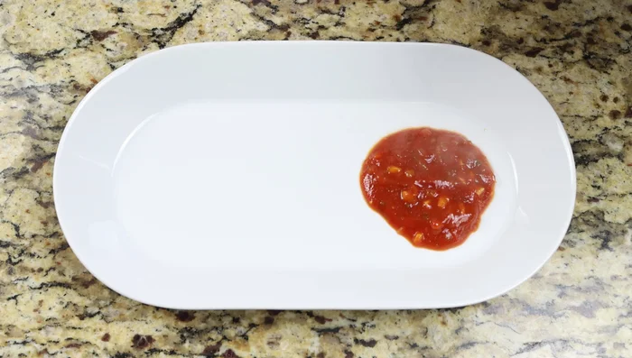Retirar del fuego, transferir la salsa de tomate a una fuente para servir, cubrir con las sardinas y decorar con perejil y limón.