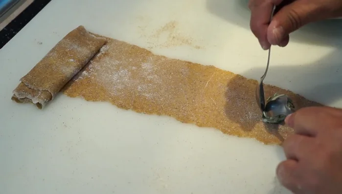 Armado de los raviolis: Colocar cucharadas pequeñas de relleno sobre la masa estirada (492.24). Pintar los bordes con agua (509.879). Doblar la masa y sellar los bordes presionando con los dedos (536.44). Cortar los raviolis con un cuchillo o cortapastas (557.839).