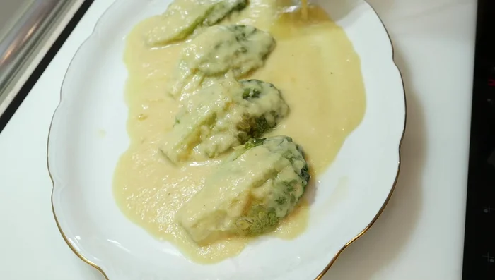 Emplatar los cogollos, cubrir con la salsa triturada, añadir una anchoa (o salmón, u otro pescado cocido) por encima y espolvorear con queso rallado.