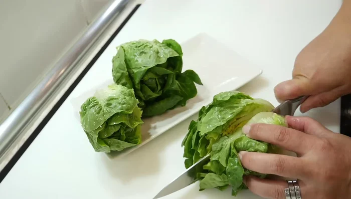 Cortar los cogollos de lechuga por la mitad y limpiarlos.