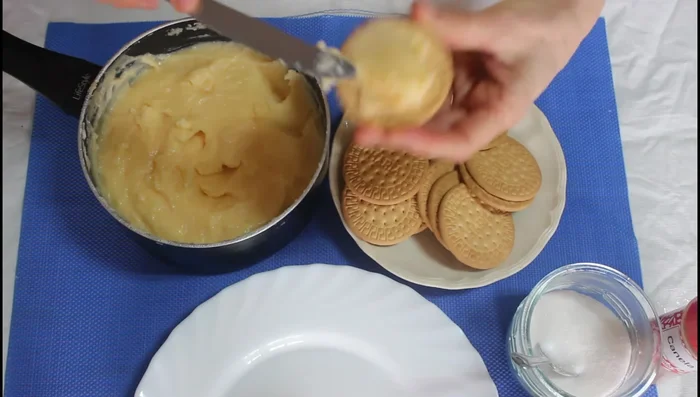 Unta una capa generosa de crema pastelera fría sobre una galleta María. Coloca otra galleta encima para formar un bocadillo.