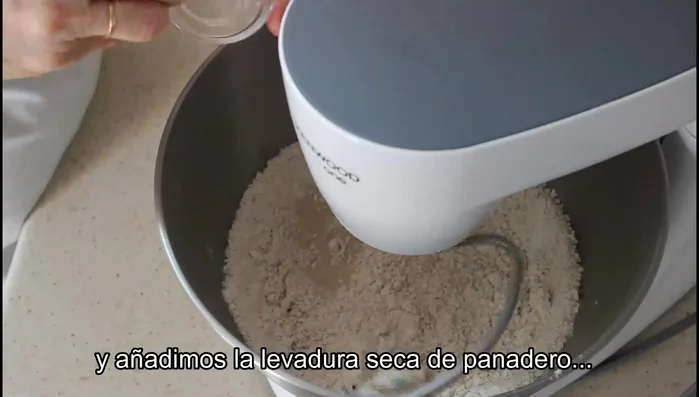Añadir la levadura seca de panadero y seguir mezclando. Incorporar el agua templada poco a poco mientras se amasa.