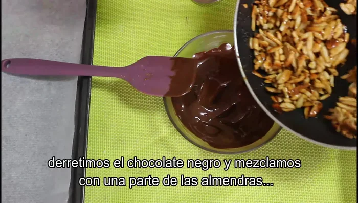 Derretir el chocolate negro. Mezclar con una parte de la mezcla de almendras. Despegar las almendras si se han pegado.