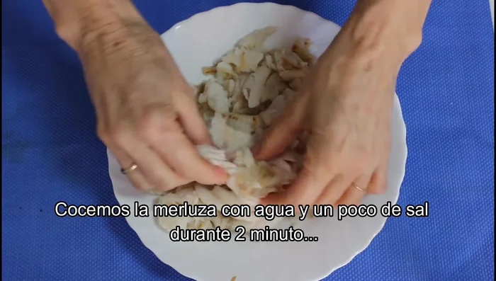 Cocer la merluza con agua y sal durante 2 minutos. Escurrir bien y desmenuzarla. Reservar el caldo.