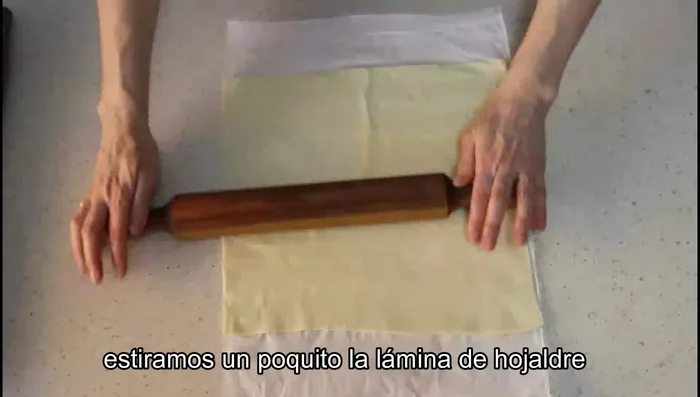 Extender una lámina de hojaldre sobre la mesa y poner el relleno de atún encima, dejando 1 cm de borde. (54.039)