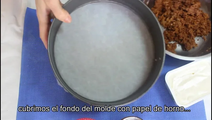 Forrar el fondo del molde con papel de horno y colocar la mezcla de galletas y mantequilla, presionando para compactar.