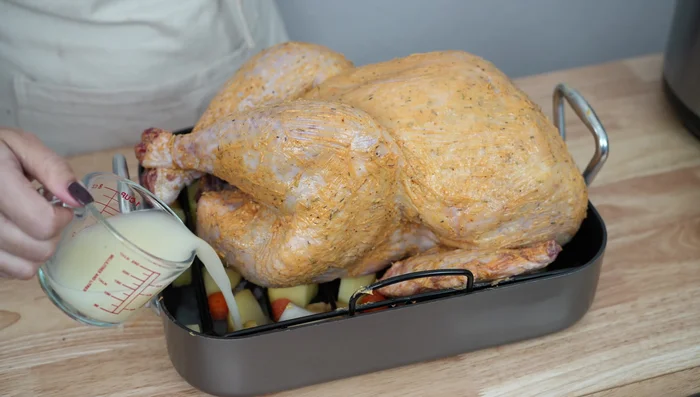 Hornear el pavo: Colocar el pavo relleno sobre la base de verduras. Agregar vino blanco y caldo. Hornear a 200°C durante 20-30 minutos, luego bajar la temperatura a 160°C y hornear durante 4 horas más. Cubrir con papel aluminio para evitar que se queme. Rociar con el líquido que suelta cada 30 minutos. En los últimos 10 minutos, subir la temperatura a 180-200°C para dorar.