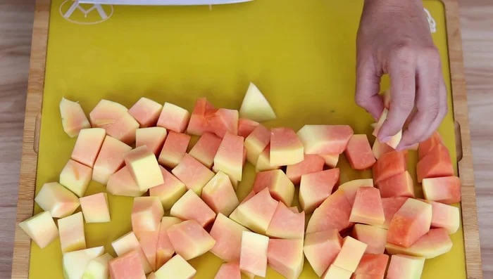 (Variante 2) Sumergir la otra mitad de la fruta bomba pelada y cortada en cubos en agua con bicarbonato de sodio (opcional).