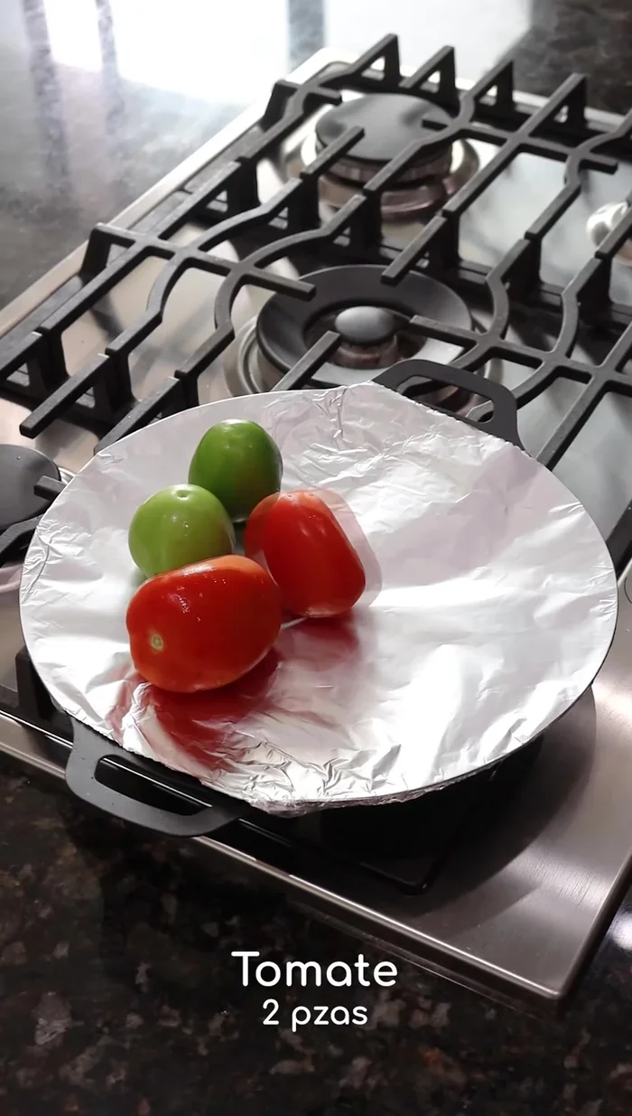 Mientras tanto, en un comal, asar 2 tomatillos, 2 tomates, un trozo de cebolla, 2 dientes de ajo, 2 chiles serranos y 3 chiles de árbol hasta que estén bien tatemados.
