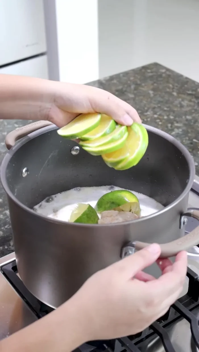 Agregar el jugo de una naranja, 3 rodajas de naranja, 4 hojas de laurel, 4 dientes de ajo más y 300 ml de refresco de cola. Mezclar con las pinzas.