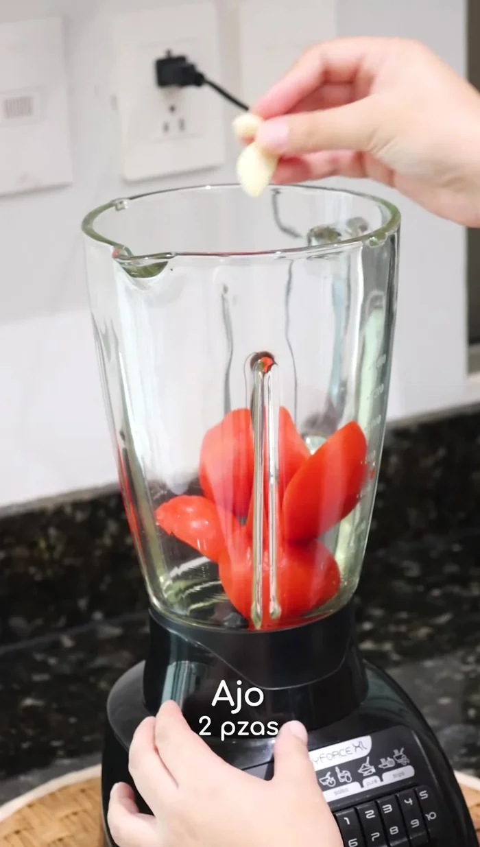 Preparar el arroz: Sofreír arroz con tomates, ajo, cebolla, sal y consomé de pollo licuados previamente.