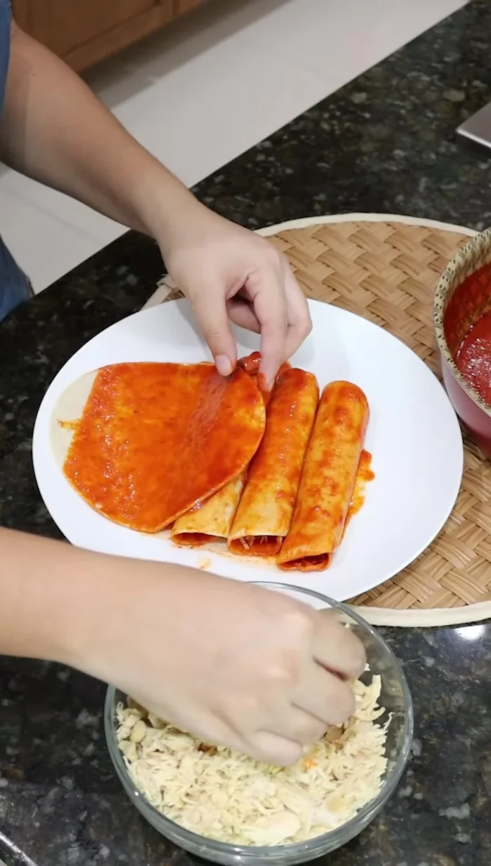 Rellenar las tortillas de maíz con la pechuga de pollo cocida y formar taquitos.