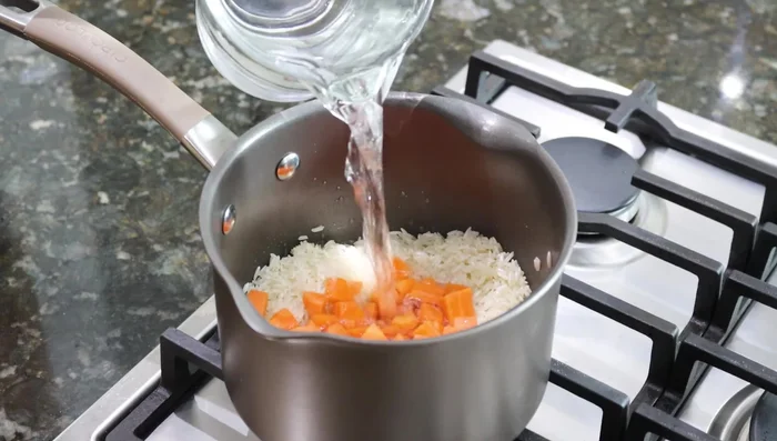 Agregar 3 zanahorias en cubitos, 2 tazas de agua, ajo en polvo y sal al gusto. Mezclar y tapar.
