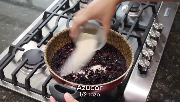 Una vez que la Jamaica haya comenzado a hervir (aprox. 5 min), agrega media taza de azúcar y las fresas cortadas. Mezcla hasta que las fresas estén suaves.
