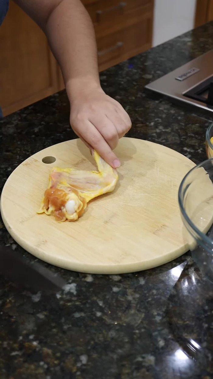 Colocar las alitas sobre una tablita, cortar la punta y luego partirlas a la mitad.