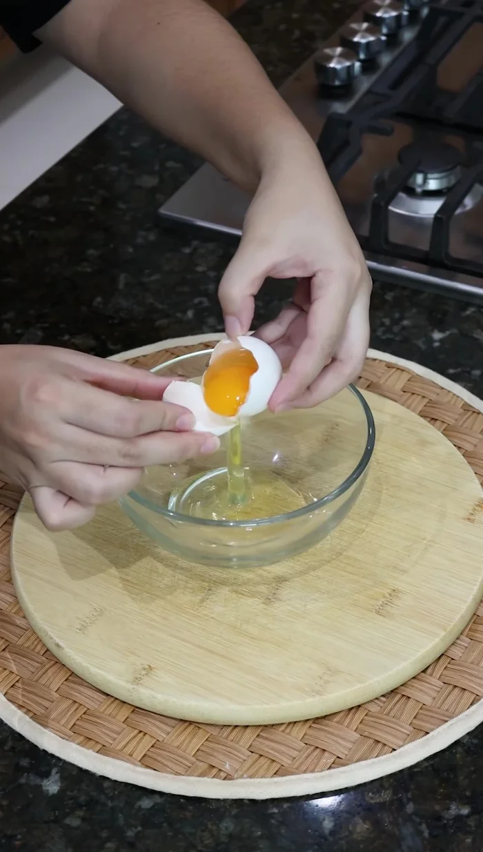 Separar las yemas de dos huevos y mezclarlas con tres cucharadas de azúcar en un recipiente.