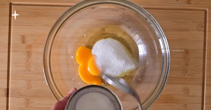 Prepara la mezcla: Bate los 2 huevos grandes, 3 cucharadas de azúcar, 4 cucharadas de queso crema, 100g de coco rallado, 1 cucharadita de polvo de hornear y 1 cucharadita de esencia de vainilla.