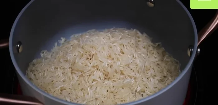 Para el arroz: Calentar una cucharada de aceite en una olla. Agregar el arroz enjuagado y freírlo a fuego medio-alto hasta que esté ligeramente tostado.