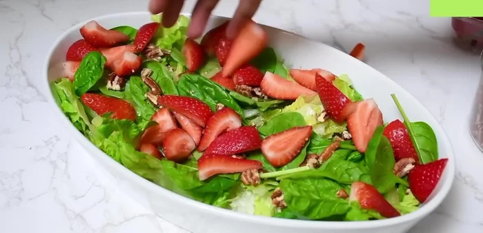 Agregar las fresas reservadas y decorar la ensalada.