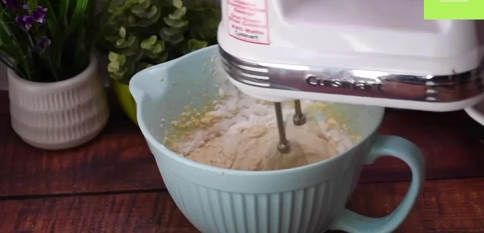 Incorpora la harina poco a poco, usando la batidora eléctrica, hasta obtener una mezcla homogénea y espesa.
