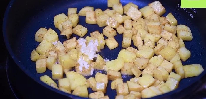 Agregar ajo picado, un poco más de aceite, pimiento rojo y cebolla a la sartén con las papas. Sofreír hasta que las papas estén suaves.