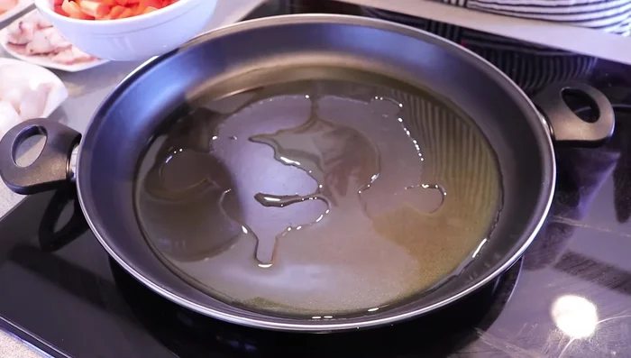 Calentar el aceite en la paella. Freír el pimiento, el tomate y el ajo hasta que el tomate pierda el agua y se fría.