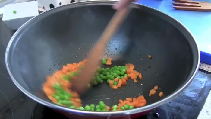 Sofreír ingredientes: En una sartén o wok, sofreír la zanahoria, guisantes, jamón, y langostinos/gambas hasta que estén listos. Reservar.