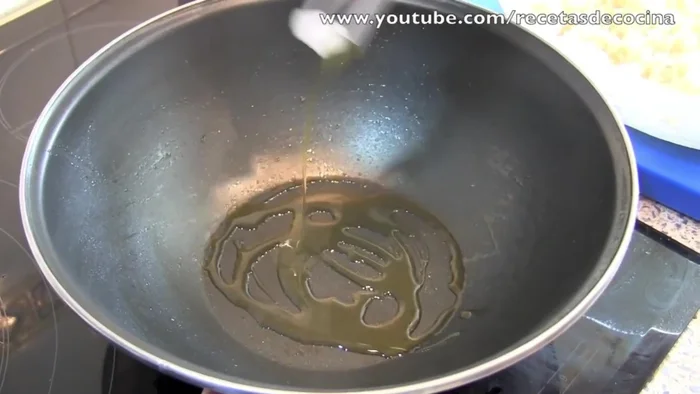 Freír el arroz: Agregar aceite al wok, añadir el arroz frío y mover constantemente para freírlo bien. Añadir el huevo batido y seguir moviendo.