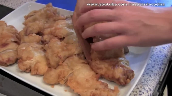 Montar el pollo al limón: Cortar el pollo rebozado en tiras. Colocar en una fuente, cubrir con rodajas de limón y la salsa de limón templada.