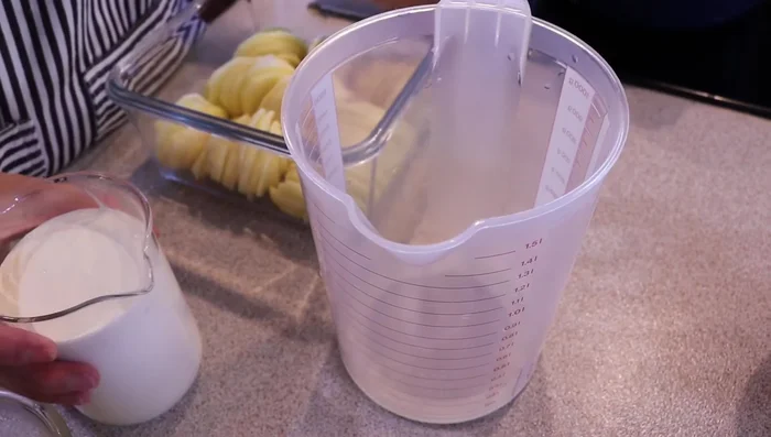 Preparar la mezcla de nata y leche. Añadir aproximadamente la mitad de leche que de nata. Incorporar la mantequilla, ajo picado, nuez moscada, pimienta y sal al gusto. Ser generosos con la nuez moscada y la pimienta, ya que la patata y la nata son sabores suaves.