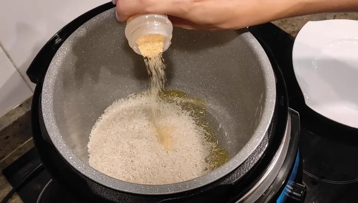 Incorpora un poquito de ajo en polvo (o un diente de ajo fresco picado) y sal. Sofríe el arroz hasta que esté empapado en aceite y chisporrotee.
