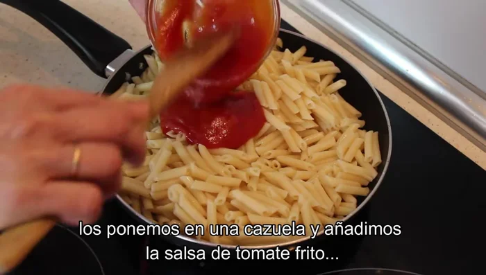 En una sartén o cazuela, poner los macarrones escurridos, añadir la salsa de tomate frito y mezclar.