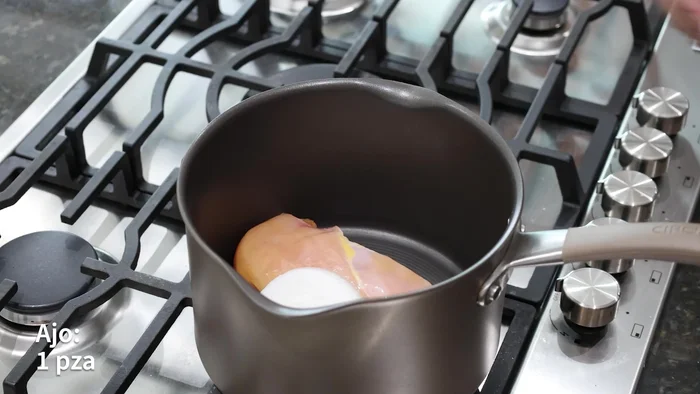 En otra olla, cocinar una pechuga de pollo con una rodaja de cebolla, un diente de ajo, dos hojas de laurel, agua suficiente para cubrir la pechuga y sal al gusto. Cocinar de 25 a 30 minutos.